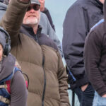 Man in an olive-green puffer jacket with short grey beard and black sunglasses gives a nazi salute